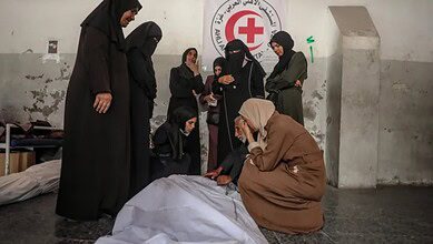 Palestinian family mourns beside bodies wrapped in white shrouds inside a hospital in Gaza.