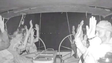 Global Sumud Flotilla activists raise their hands as Israeli forces intercept their boat at night.