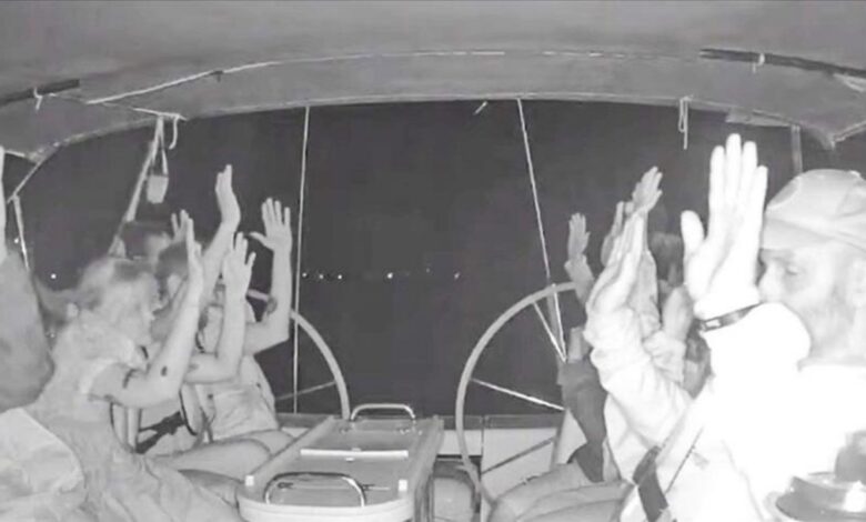 Global Sumud Flotilla activists raise their hands as Israeli forces intercept their boat at night.