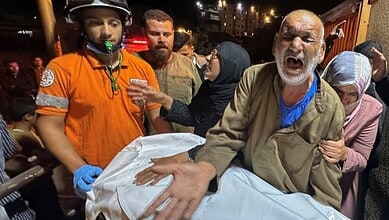 A grieving Palestinian man reacts beside a covered body after an Israeli strike on Tuesday night, October 28.
