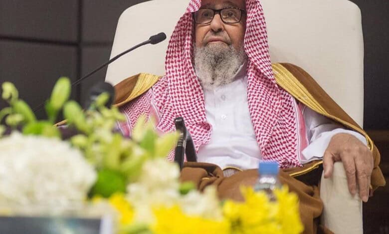 Sheikh Saleh Al-Fawzan seated during an official event, wearing a traditional Saudi robe and red-and-white ghutra.