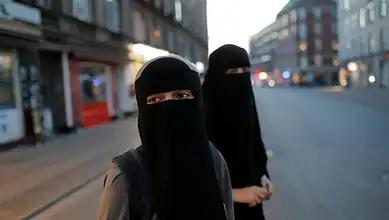 Representative image showing two women wearing black niqabs walking along a city street.