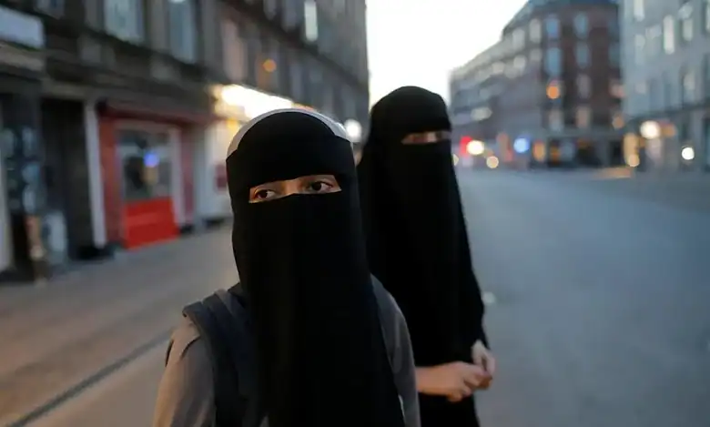 Representative image showing two women wearing black niqabs walking along a city street.