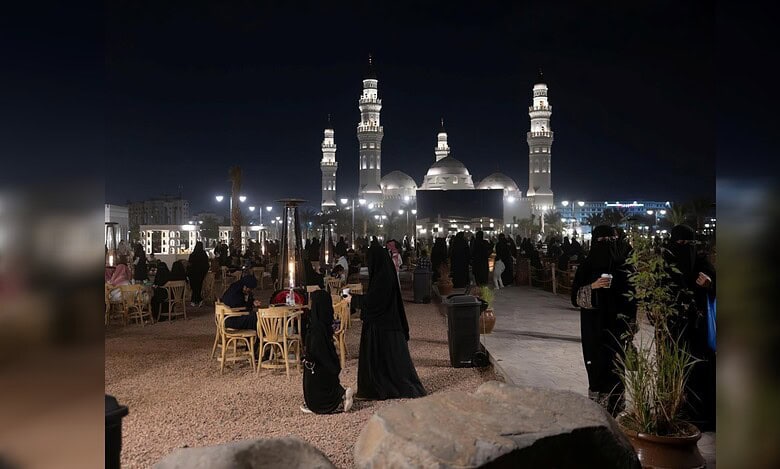 Night-time view of visitors and families at the outdoor promenade near Quba Mosque in Madinah city.