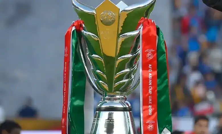 A close-up view of the AFC Asian Cup trophy with red and green ribbons from the UAE 2019 tournament.