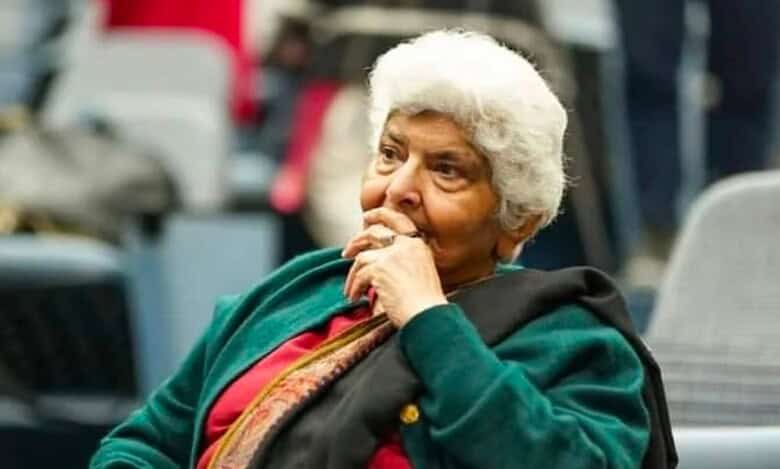 Dr Arfa Sayeda Zehra seated during an event, wearing a green shawl and red outfit, appearing thoughtful and composed.