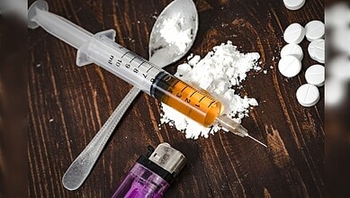 Syringe, white powder and pills representing illegal drug use.