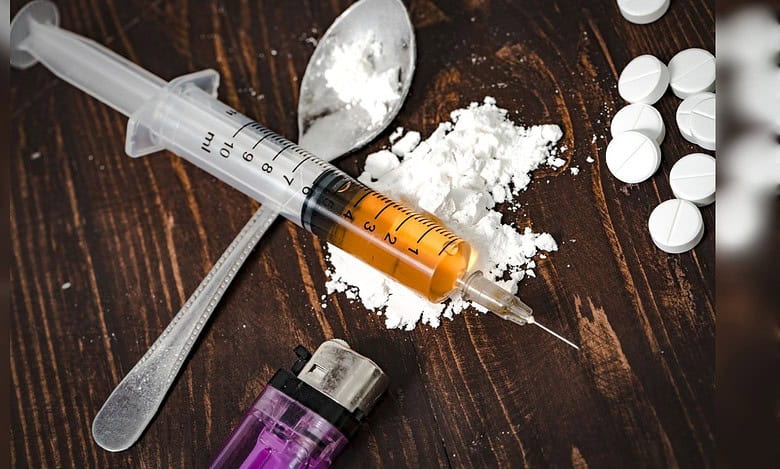 Syringe, white powder and pills representing illegal drug use.
