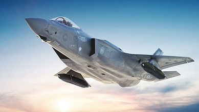 F-35 stealth fighter jet flying against a clear sky at sunrise.