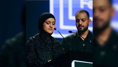 Hind Rajab’s mother speaks emotionally at a podium beside a man during a film festival event.