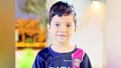 A 6-year-old boy, identified as Issa Al Zahir, smiling while wearing a dark T-shirt with pink and white accents.