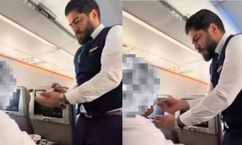 A Saudia Airlines flight cabin crew member gently feeds an elderly Umrah passenger dressed in ihram during a flight.
