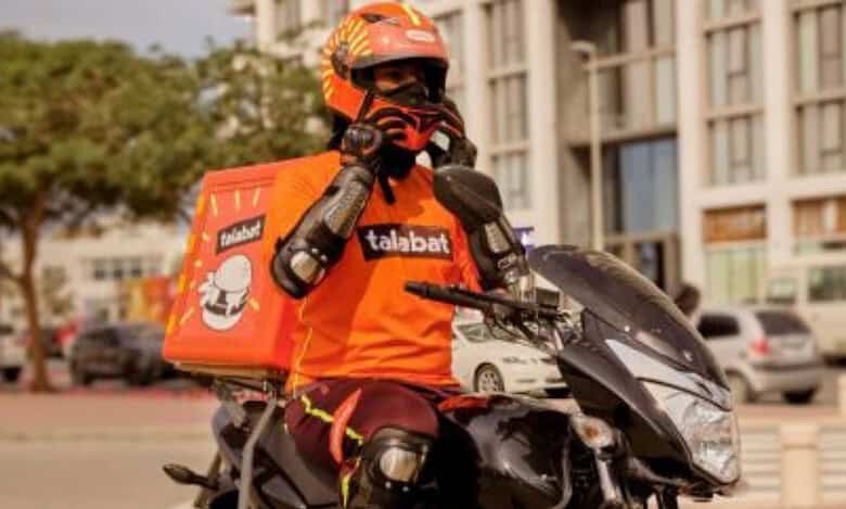 A delivery rider wearing protective gear and a helmet sits on a motorcycle in the UAE.