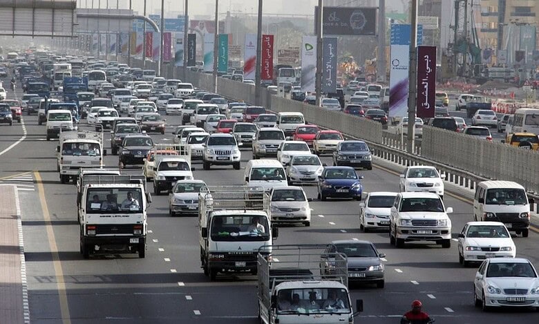 Heavy traffic on Sheikh Zayed Road in central Dubai with multiple lanes filled with cars and trucks.