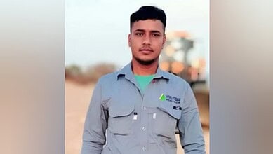 A man wearing a grey Hyundai Engineering uniform stands outdoors, looking at the camera. The background appears to be a sandy worksite in daylight.