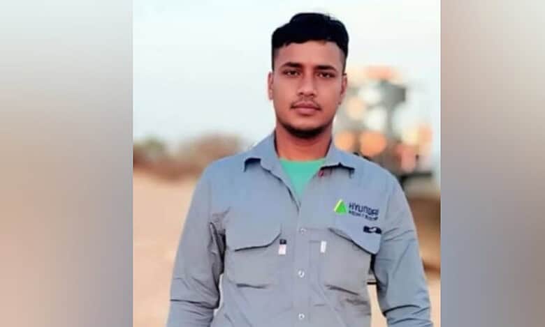 A man wearing a grey Hyundai Engineering uniform stands outdoors, looking at the camera. The background appears to be a sandy worksite in daylight.