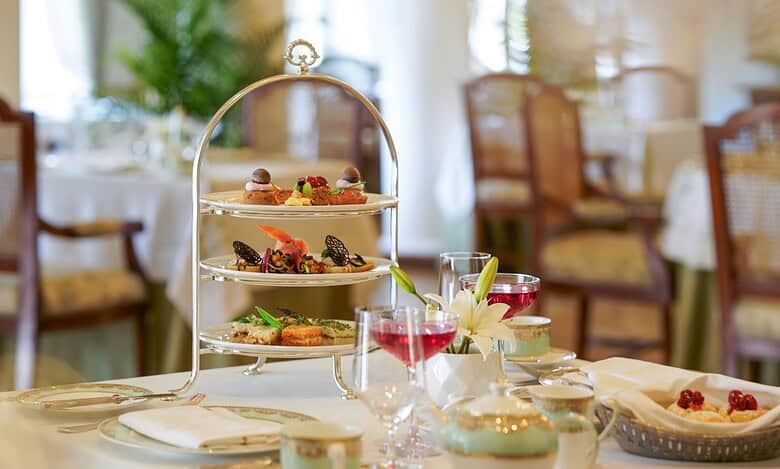 Elegant afternoon tea service with three-tiered stand, fine china, and colorful beverages at Taj Falaknuma Palace, Hyderabad