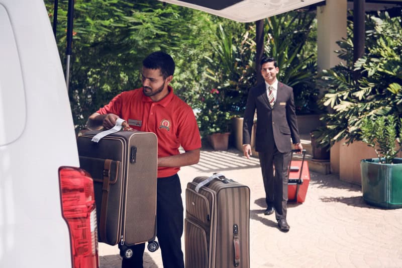 Emirates staff collects luggage during home check-in service.