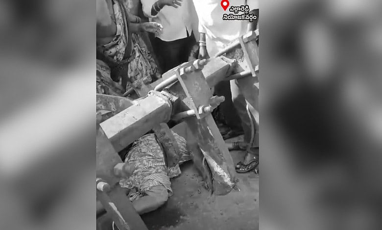 A black and white image showing a woman lying under a tractor.
