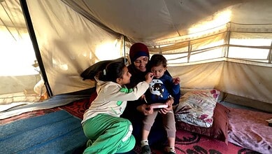 A woman sits with children in Gaza camp