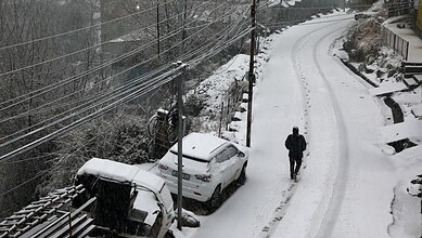 A man walks through snow amid fresh snowfall at Bhaderwah, in Doda district, Jammu and Kashmir