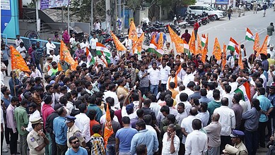 Image shows a large crowd holding saffron flags