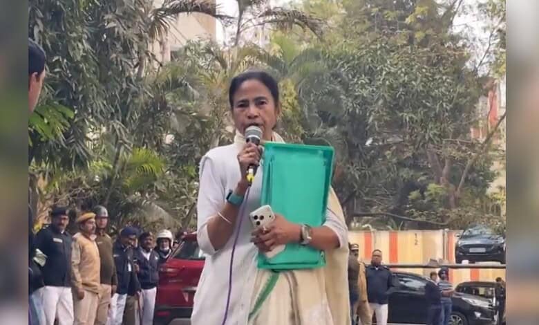 Image shows TMC chairperson Mamata Banerjee speaking in a microphone and holding a green file