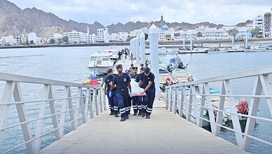 Royal Oman Police carry a dead body after boat capsizes