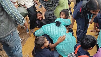 Image shows a woman hugging children after a bus accident