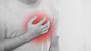 image shows A person clutching their chest with a red overlay indicating heart pain or discomfort.