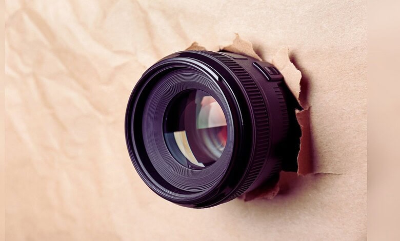 Image shows a hidden camera emerging from a cardboard wall