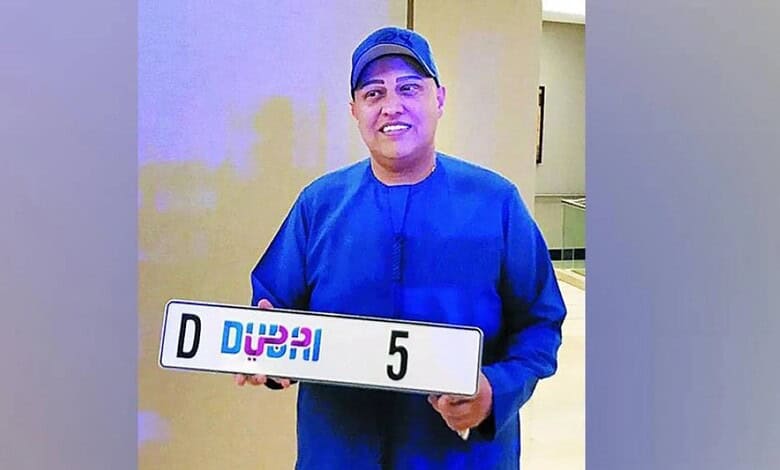 Indian businessman Abu Sabah holding Dubai number plate 5 after auction purchase.