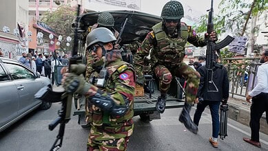Armed soldiers at polling station during Bangladesh elections, violence reported.