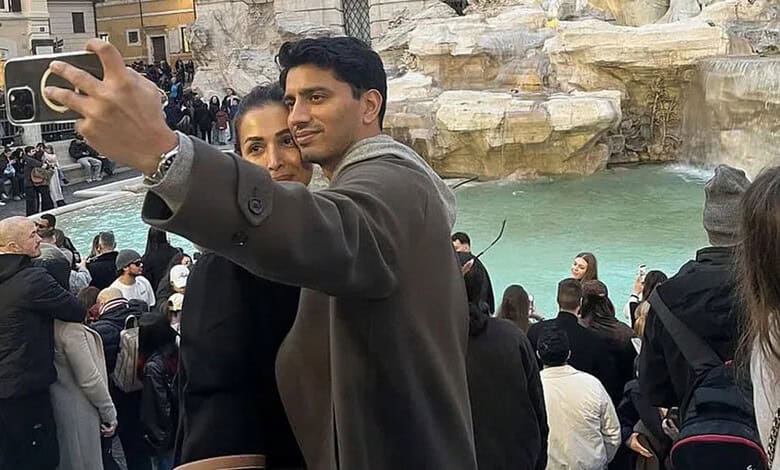 Malaika Arora taking a selfie with a man in Italy, surrounded by tourists and scenic water features.