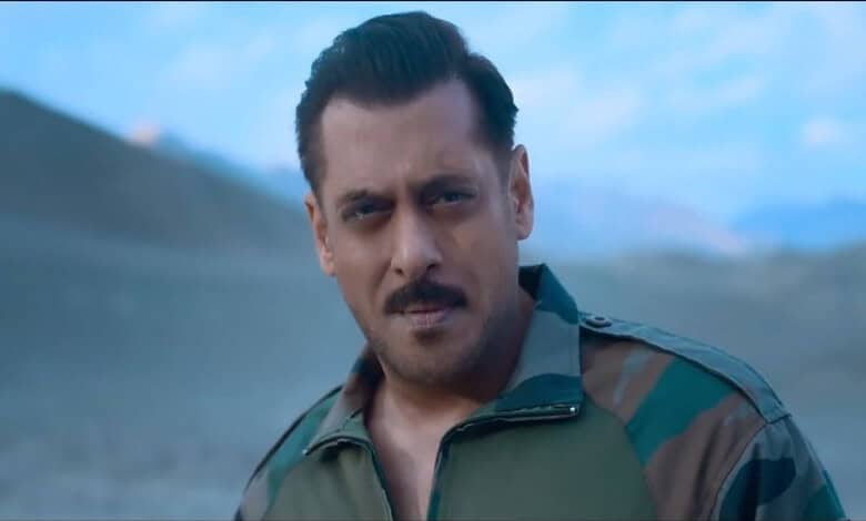 A man in military attire outdoors with mountains in the background.