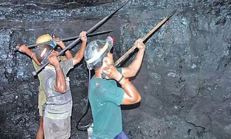 Mining workers inspecting a dark underground tunnel with tools and helmets.