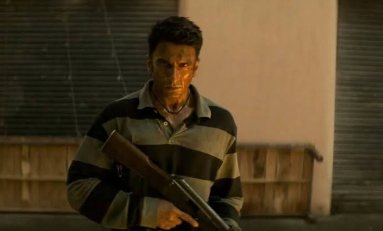 Man holding a gun in a dimly lit setting, intense expression, film scene.