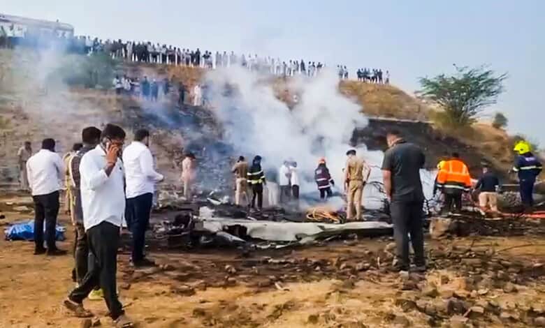 Scene of plane crash in Baramati with officials and onlookers present.