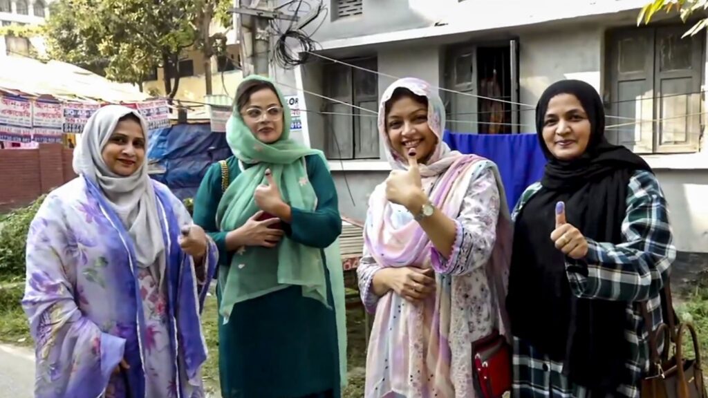 Women voters participating in Bangladesh elections, giving thumbs up.