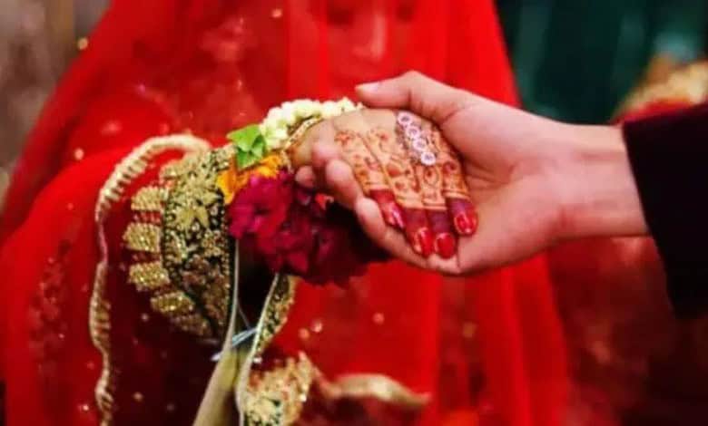 Up of a handshake between bride and groom, highlighting traditional wedding attire and henna designs.