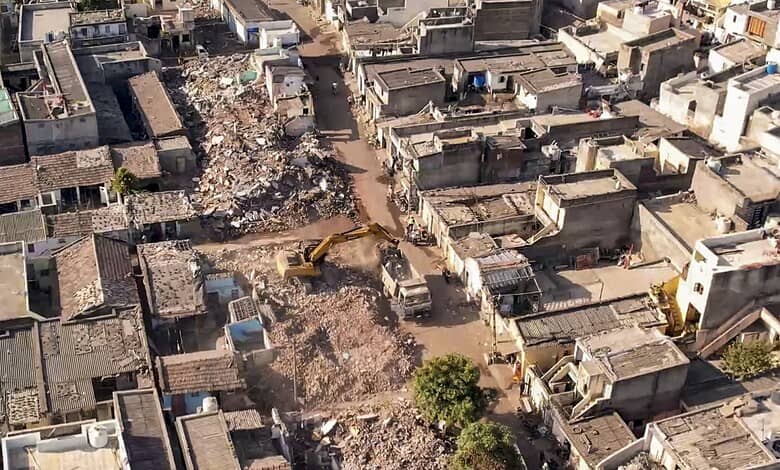 Demolition drive in Rajkot with heavy machinery tearing down 1,489 houses, marking the end of the clearan.