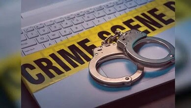 Handcuffs placed on a laptop keyboard with crime scene tape reading "CRIME SCENE" in the background.
