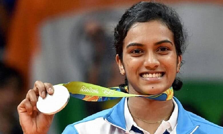PV Sindhu holding her Olympic silver medal, smiling after winning at Rio 2016.