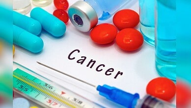 Image showing Medical supplies including capsules, tablets, syringes, and vials surrounding a card with the word "Cancer" written on it.