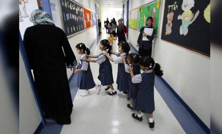 Young children in UAE school hallway with teacher, following new admission age rules.