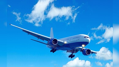 Image shows A large commercial airplane with landing gear deployed flies through a bright blue sky with scattered white clouds.