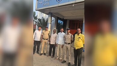 Group of men and police officers outside a government building in India.