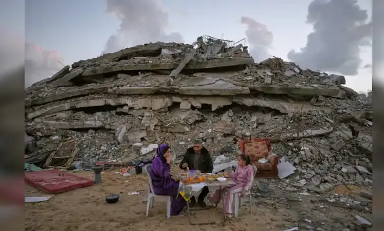 Ruins in Gaza after airstrike; family gathers amid destruction.