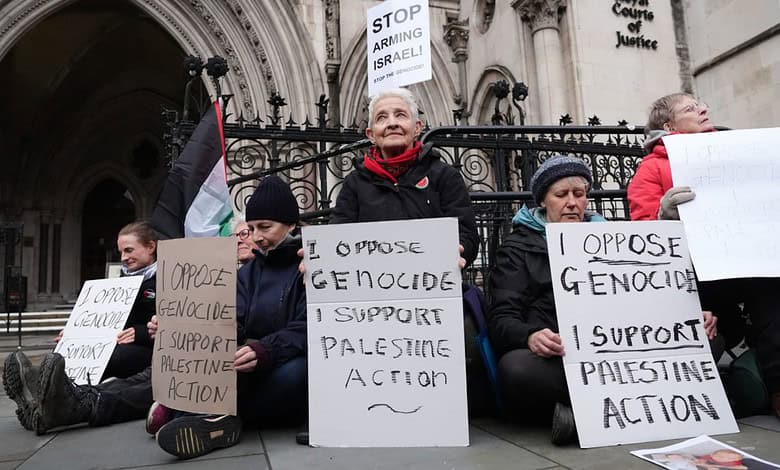 Palestine activists hold signs opposing genocide and supporting Palestinian action outside the High.