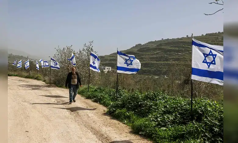 Palestinian man walks past Israeli flags near Al-Masoudiya railway site in occupied West Bank.